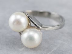 This luxurious pearl ring has a classical bypass style that is timeless! The pearls sit in the center of curving, polished heads with perfectly proportioned prongs. Easy to wear day or night, this pretty pearl ring is classic and timeless. Metal: 10K White Gold Gem: 2 Pearls Gem Measurements: 6.4 mm, Round Ring Size: 6 Marks: "10K" Stamped on the inside band Classic White Bypass Ring For Formal Occasions, White Gold Pearl Ring, Aquamarine Cocktail Ring, White Pearl Ring, Gold Pearl Ring, Demantoid Garnet, Simple Pearl, Bypass Ring, Jewelry White