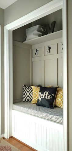 a bench with some pillows on it in a room that is painted gray and white