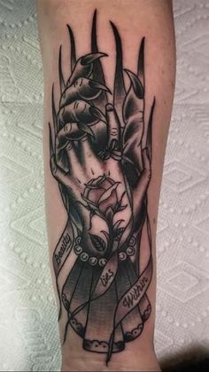 a black and white tattoo on the arm of a person with two hands holding each other