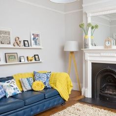 a living room with a couch, fireplace and pictures on the wall above it's mantle