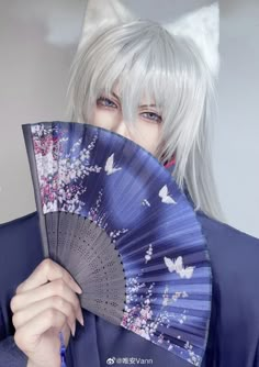 a person with white hair holding a fan