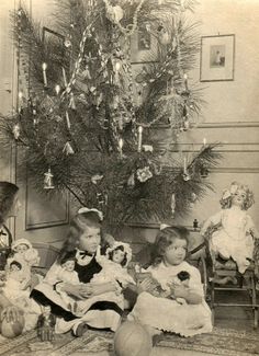 an old black and white photo of three children sitting in front of a christmas tree