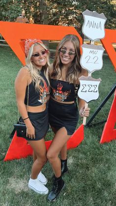 two women standing next to each other holding signs