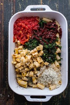 a casserole dish filled with pasta, meat and vegetables on a wooden table