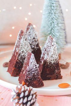 three pieces of chocolate cake on a plate with pine cones and christmas tree decorations in the background