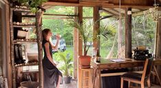 a woman standing in front of a window looking out at the yard and trees outside