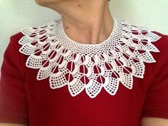 a woman wearing a red shirt with white crocheted collar