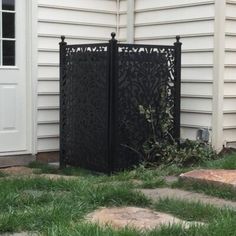 an iron gate in front of a house with grass and rocks on the ground next to it