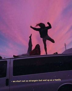 two people standing on the roof of a van with their arms up in the air