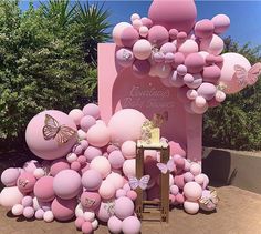 there is a pink balloon arch with balloons all over it and butterflies on the top