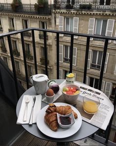 breakfast is served on the balcony of an apartment building in paris, with coffee and croissants