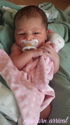 a baby laying on top of a bed with a pacifier in it's mouth