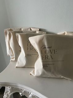 three pillows sitting on top of a white table next to each other, with the words love era printed on them