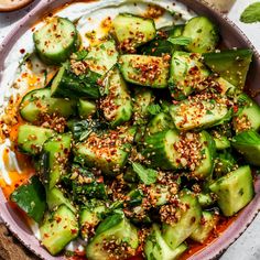 a bowl filled with cucumbers and topped with sesame seeds