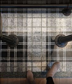 two people standing on the floor in front of a tiled area with black and white tiles