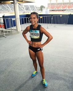 a female athlete posing for a photo in front of an empty stadium bleachers