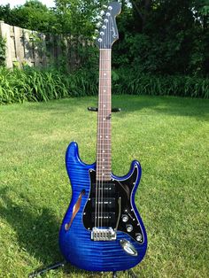 a blue guitar sitting on top of a lush green field