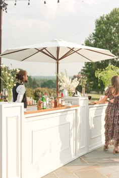 a woman standing at a bar with an umbrella over it