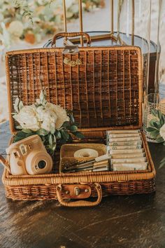 a wicker suitcase filled with books and other items on top of a wooden table