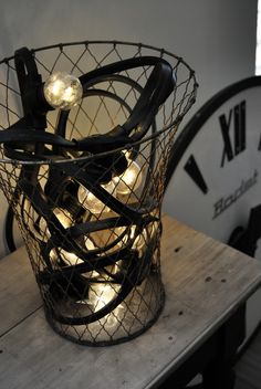 there is a wire basket with lights in it on the table next to two clocks