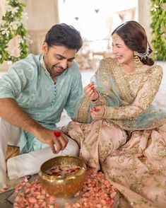 a man and woman sitting next to each other in front of a bowl of food