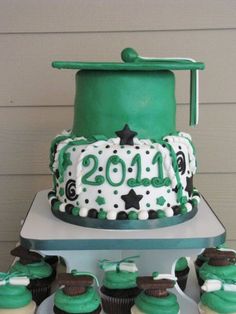 a green and white graduation cake with cupcakes