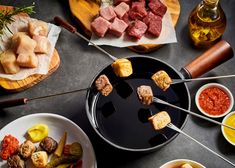 an assortment of meats and vegetables being cooked on a bbq grill with tongs