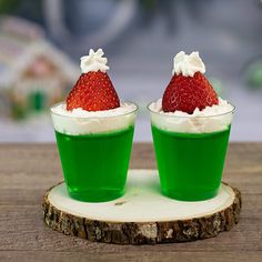 two green cups with whipped cream and a strawberry on top