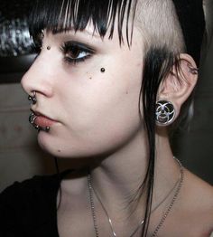 a woman with piercings on her nose and black hair