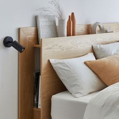 a bed with white sheets and pillows next to a wall mounted book shelf filled with books