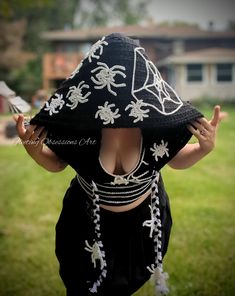 a woman wearing a black hat with white flowers on it's face and hands