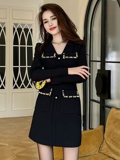 a woman standing in front of a couch wearing black dress with gold buttons on it