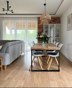 a living room and dining area with wood floors, couches, table and chairs