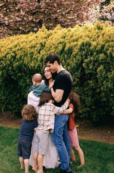 a group of people standing around each other in the grass