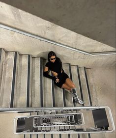 a woman sitting on top of an escalator next to a metal hand rail