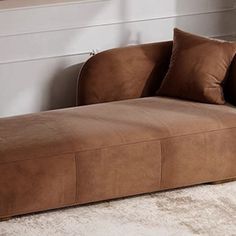 a brown couch sitting on top of a white rug