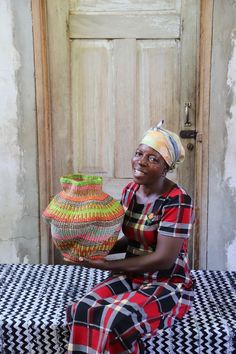 a woman sitting on top of a checkered table cloth holding a basket in front of her