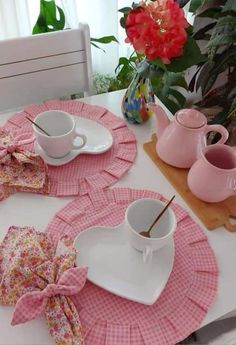 the table is set with pink and white dishes, cups, and saucers on it