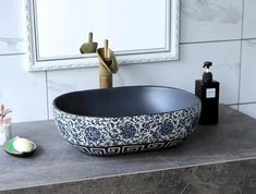 a black and white bowl sink sitting on top of a counter next to a mirror