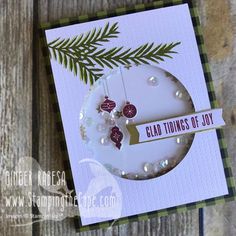 a close up of a card on a wooden surface with a tree branch in the background