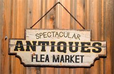 an antique flea market sign hanging on a wooden wall