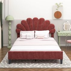 a red bed sitting on top of a wooden floor next to a pink chair and table