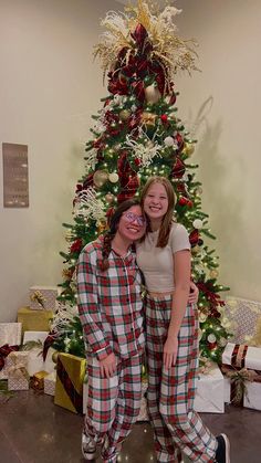 two people standing in front of a christmas tree