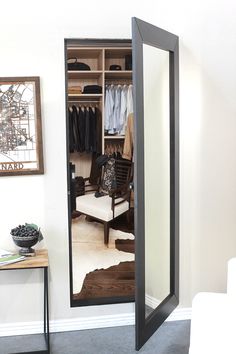 an open closet with clothes on hangers and a mirror in the door to it