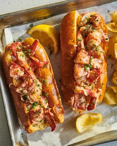 two lobster sandwiches on a tray with lemon wedges next to it and the words how sweet eats above them