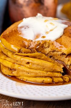 a stack of pancakes covered in syrup and whipped cream