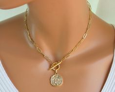 "This is a gold filled coin choker necklace for women. Ancient coin pendant is 14kt gold filled, features the Benedict cross and measures 21mm and is double sided. Paper clip chain is 14kt gold filled, links measure 11x5mm, 1mm thick with a toggle clasp in front. Very trendy this necklace is even more lovely in person. Looks great worn alone or with other necklaces! Comes in a cute gift box! Model is wearing a 15\" length. CHOSE YOUR LENGTH. Gold filled jewelry is an actual layer of gold pressur Luxury Classic Necklace With Gold Clasp, Luxury Gold Necklace With Adjustable Cord, Gold Toggle Necklace With Coin Pendant, Catholic Jewelry Necklace, Ancient Coin Pendant, Gold Coin Jewelry, 14kt Gold Jewelry, Coin Choker, Cross Gold