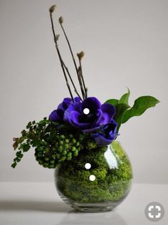 a vase filled with purple flowers and greenery