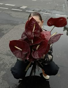 a woman kneeling on the ground with flowers in front of her face and behind her head