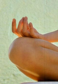 a woman is sitting on the beach with her legs crossed and hands folded in front of her